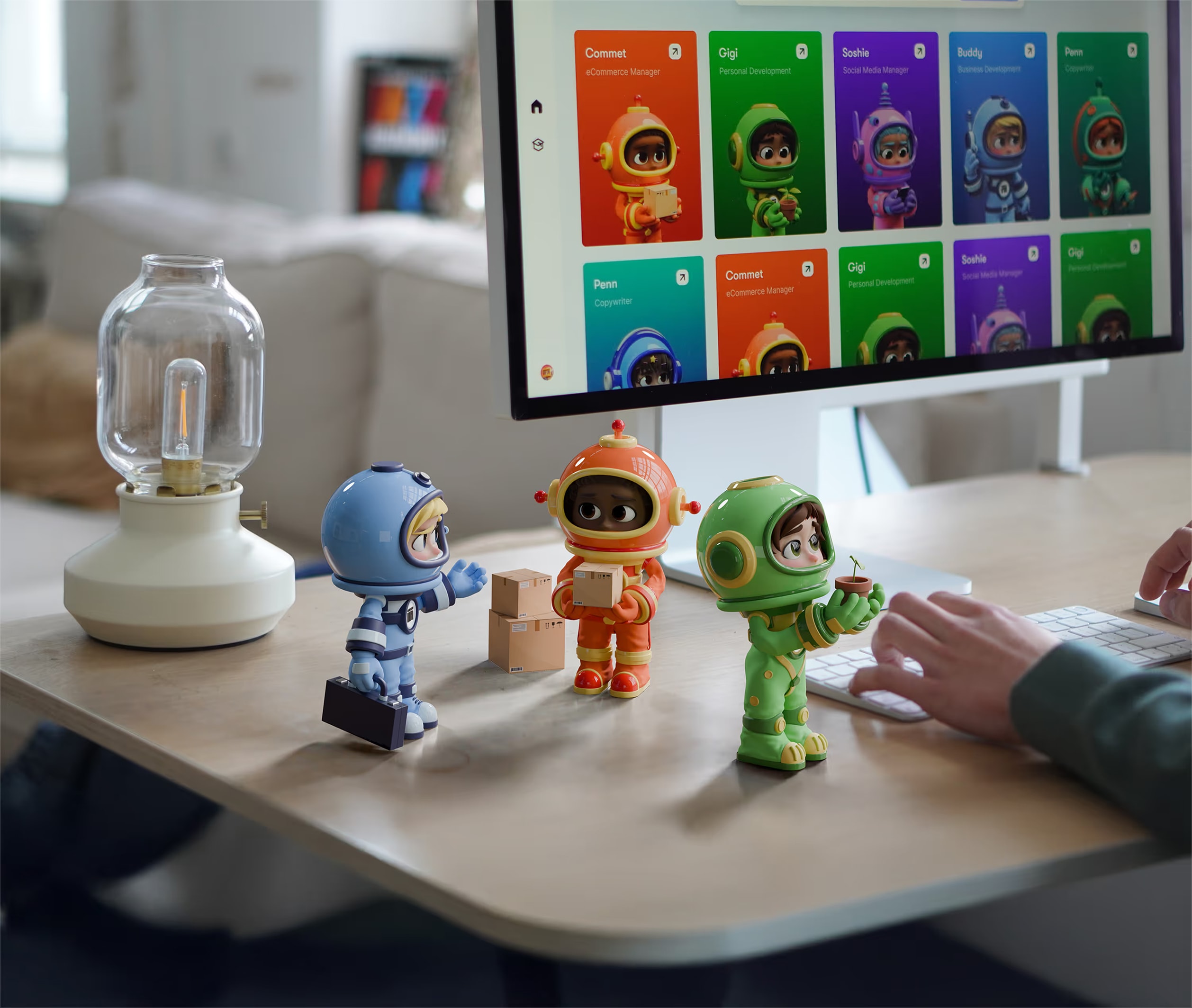Three colorful astronaut figurines standing on a desk next to a computer monitor displaying cartoon avatars and a person's hands typing on a keyboard.